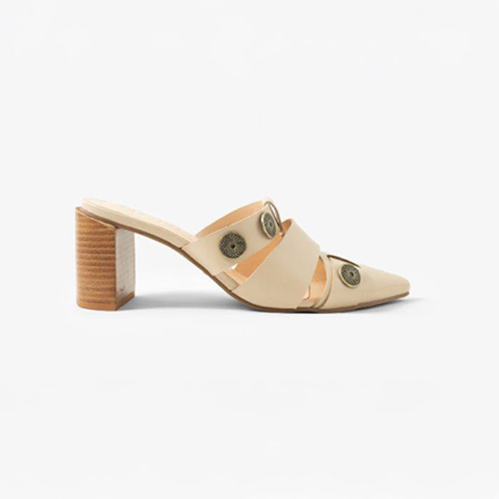 Beige brown heeled mules with cut-out straps and metal stud accents, set against a gradient blue background.