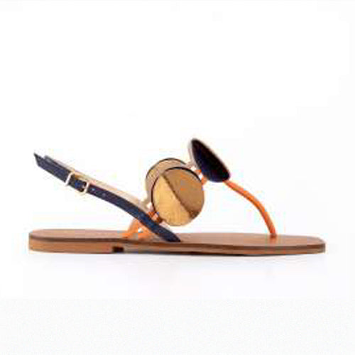 Stylish flat sandal featuring a tan footbed, thin orange t-straps, and a large gold disc ornament.  Set against a white background 