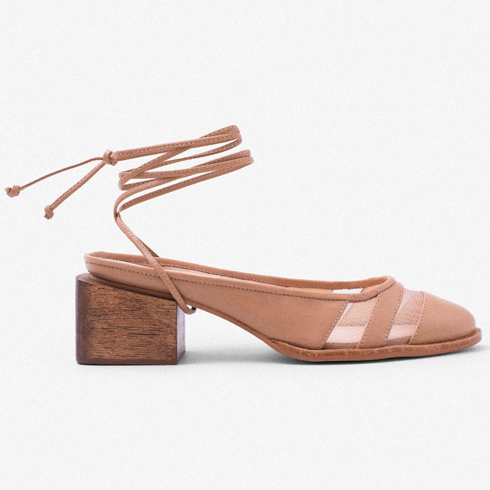 A beige slingback shoe with a wooden block heel and crisscross ankle straps, featuring a stylish mesh panel design.